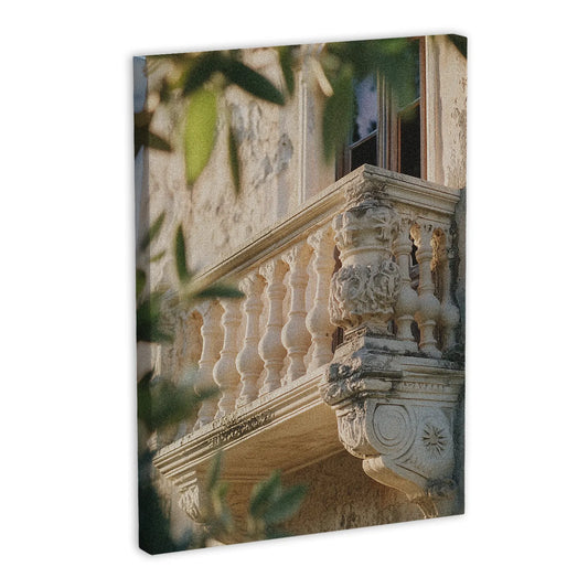 Obraz na płótnie przedstawiający zabytkowy balkon z rzeźbionymi detalami, otoczony zielonymi liśćmi.